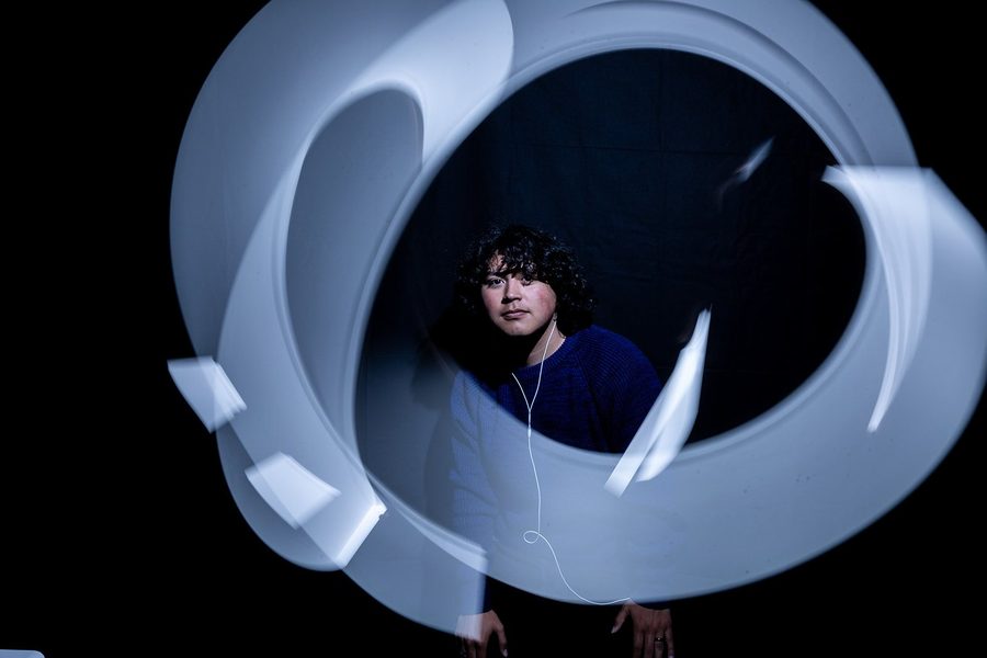 Ribbons of light spiral around a student standing in the dark