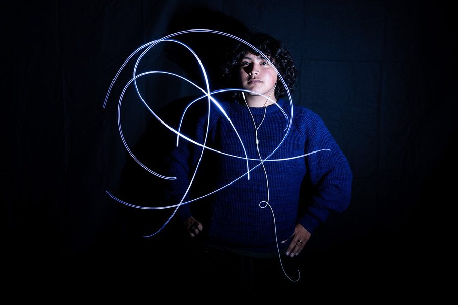 Student work: a student in a blue sweater surrounded by loops of light, a light painting photograph